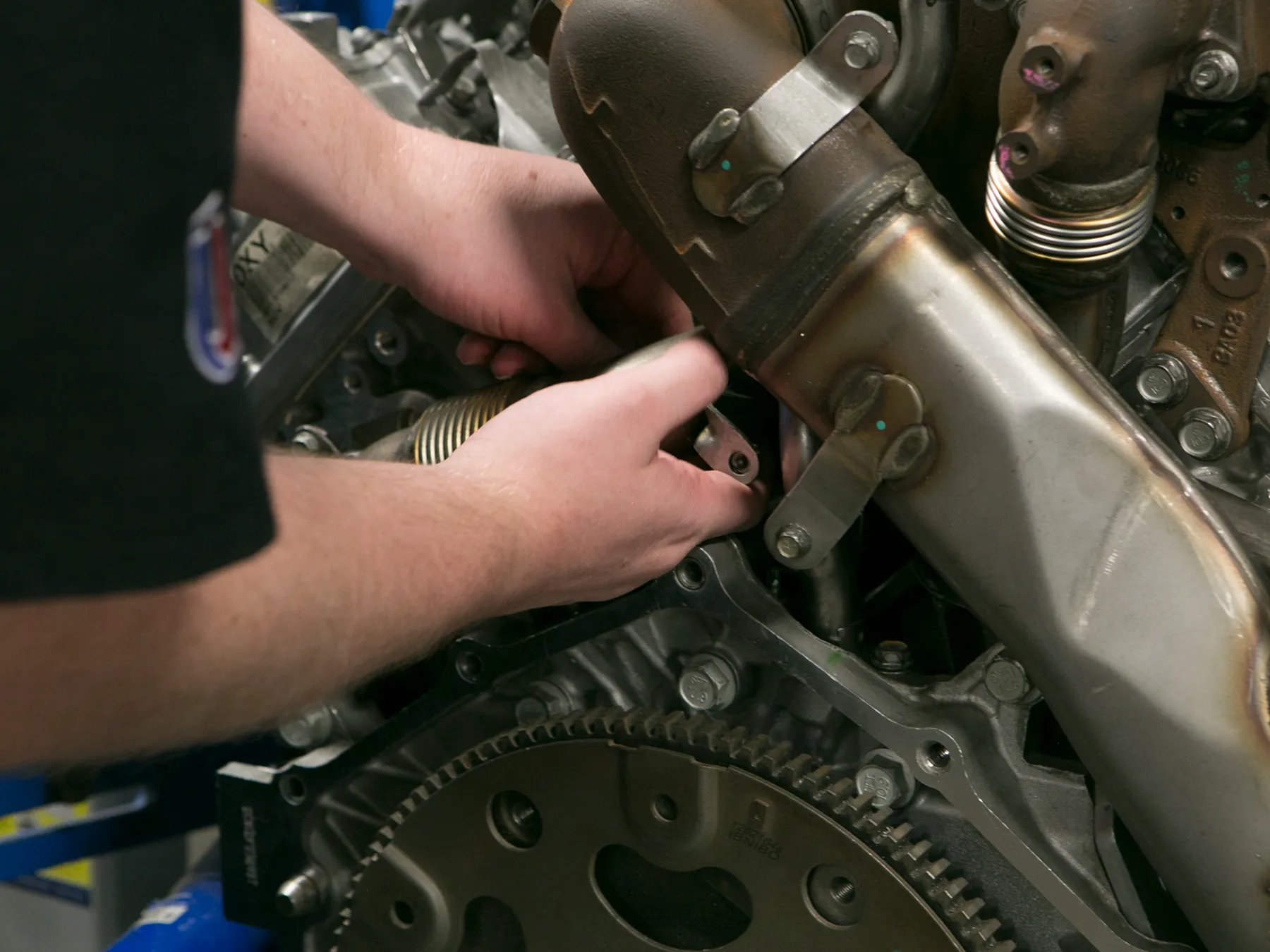 Close up on UTI student hands working on an engine