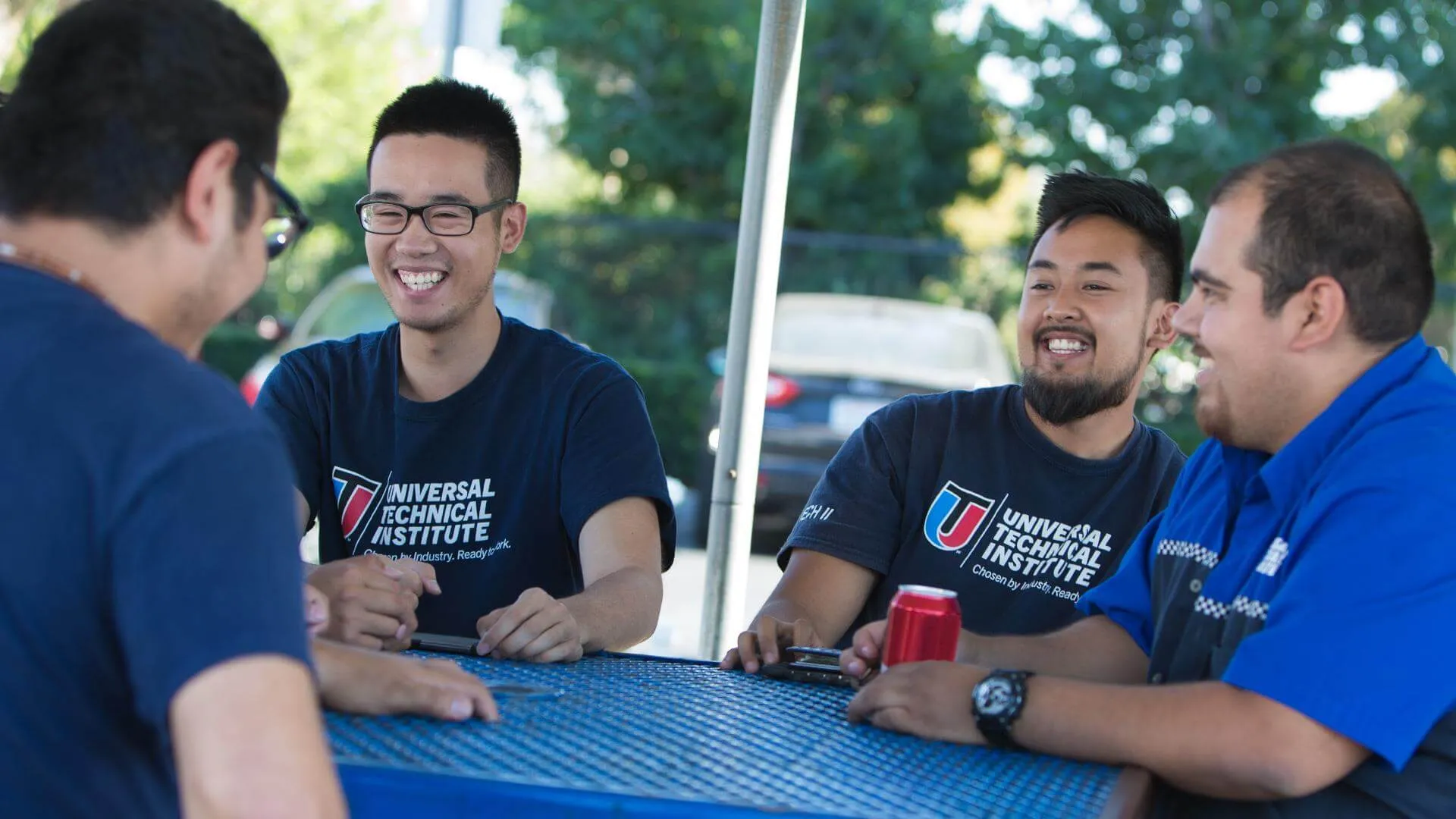 UTI students smiling on break at a blue table